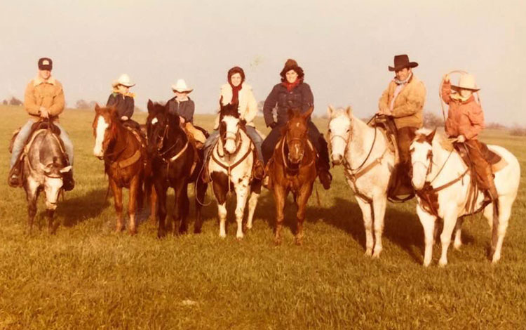 Home photo of a family of cowboys and cowgirls sitting horseback.